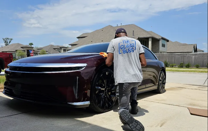 Father & Son's Mobile Detailing wiping down a burgundy Lucid Air in a customer's driveway